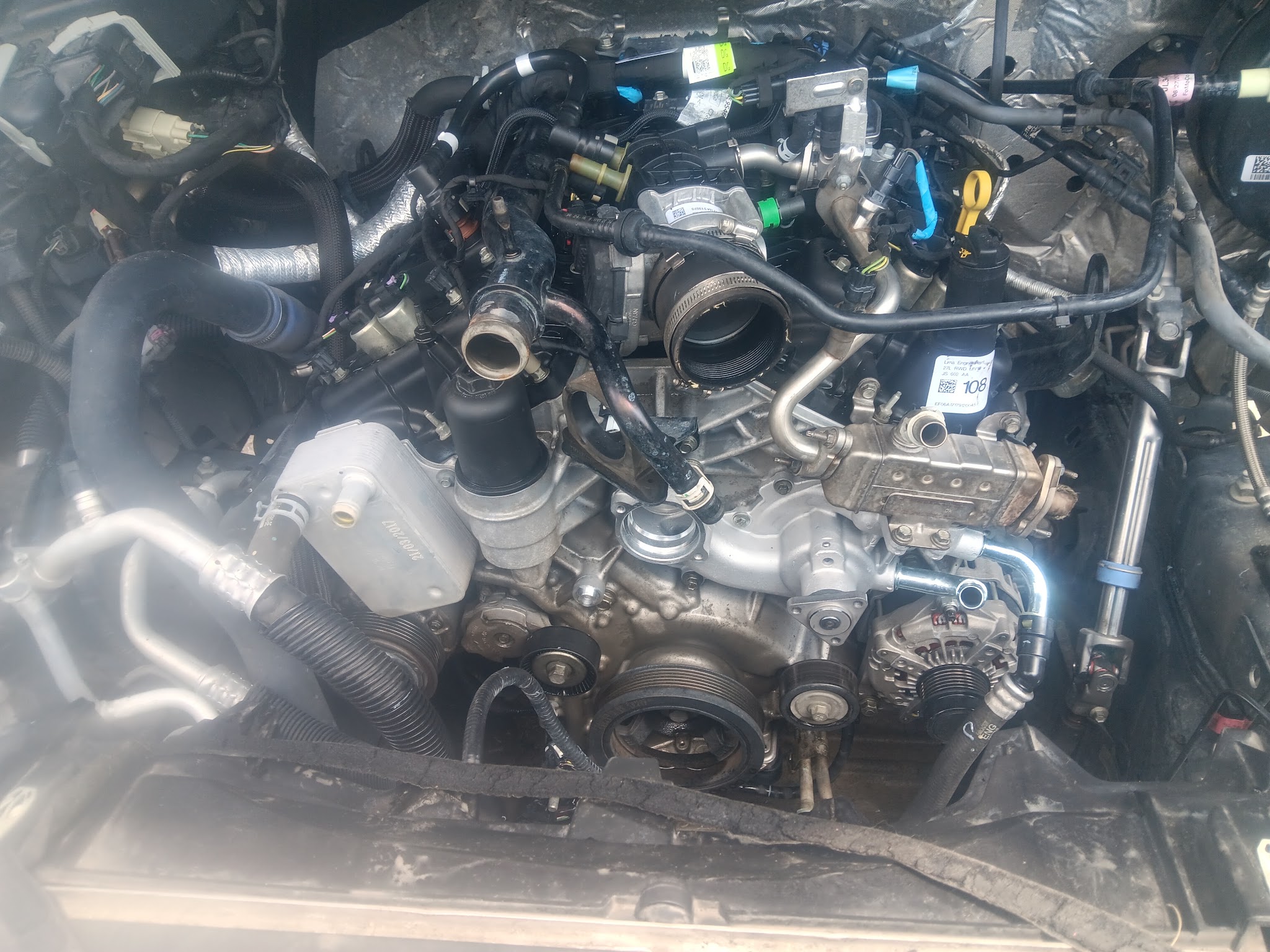 Engine bay of a truck during a repair with hoses and fittings visible